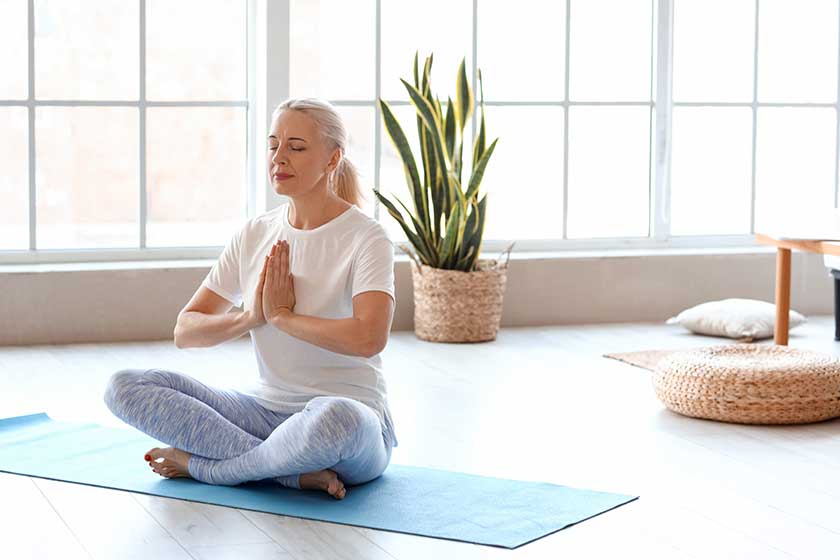 Morning of mature woman meditating at home